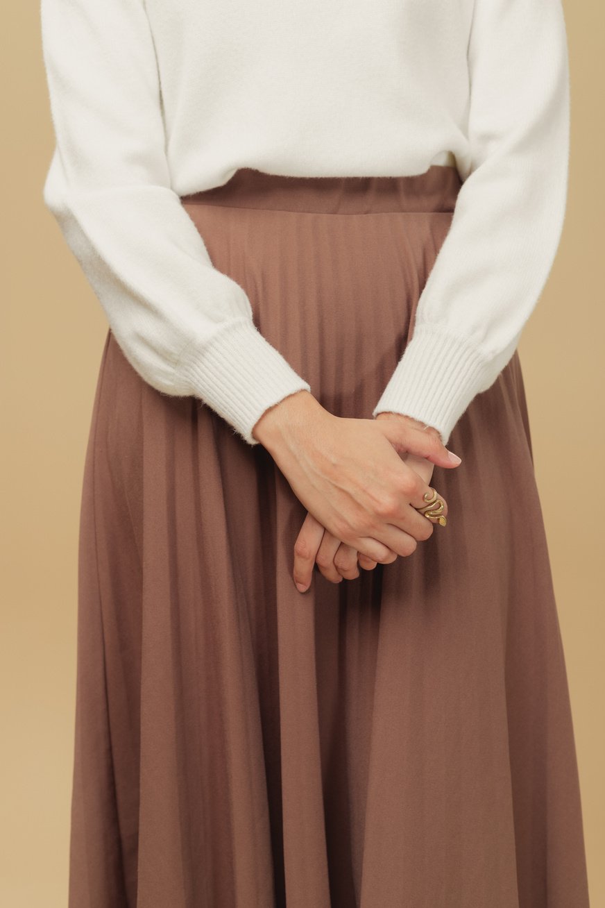 Woman in White Sweater and Brown Skirt on Beige Background